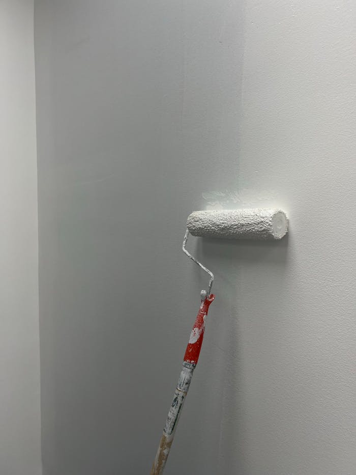 Smooth white paint applied on a wall using a roller, showcasing home renovation process.